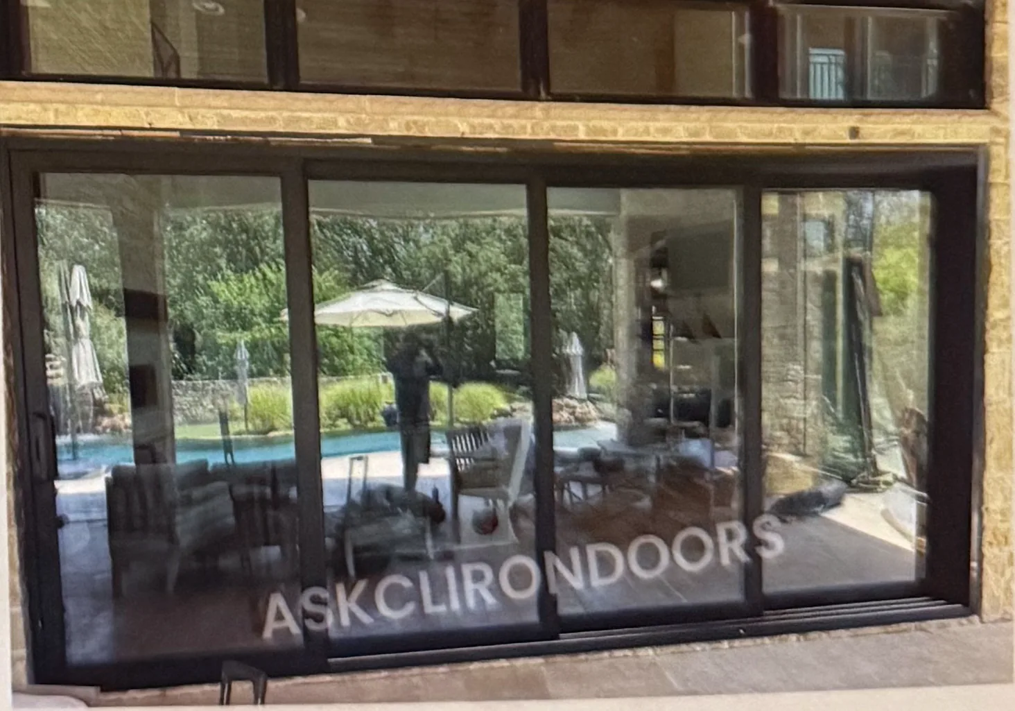 Wide multi-panel dark-framed sliding glass door opening onto a pool patio